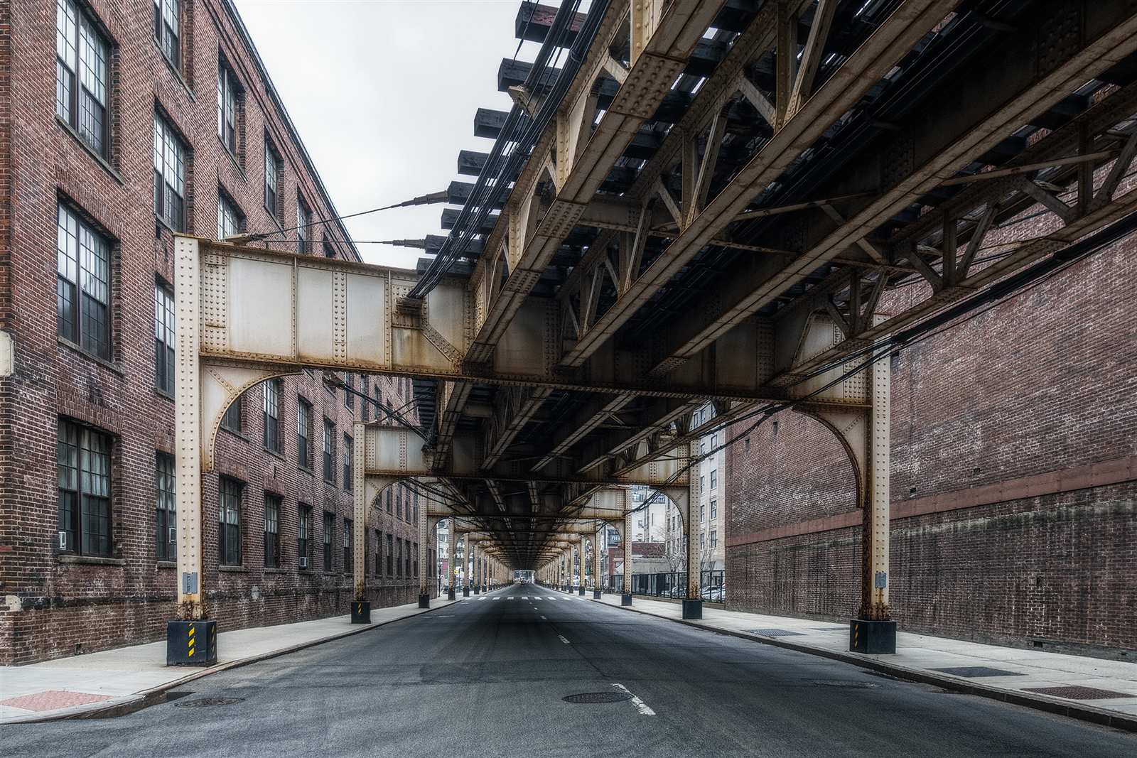 An elevated steel viaduct crossing a street beside an old brick warehouse