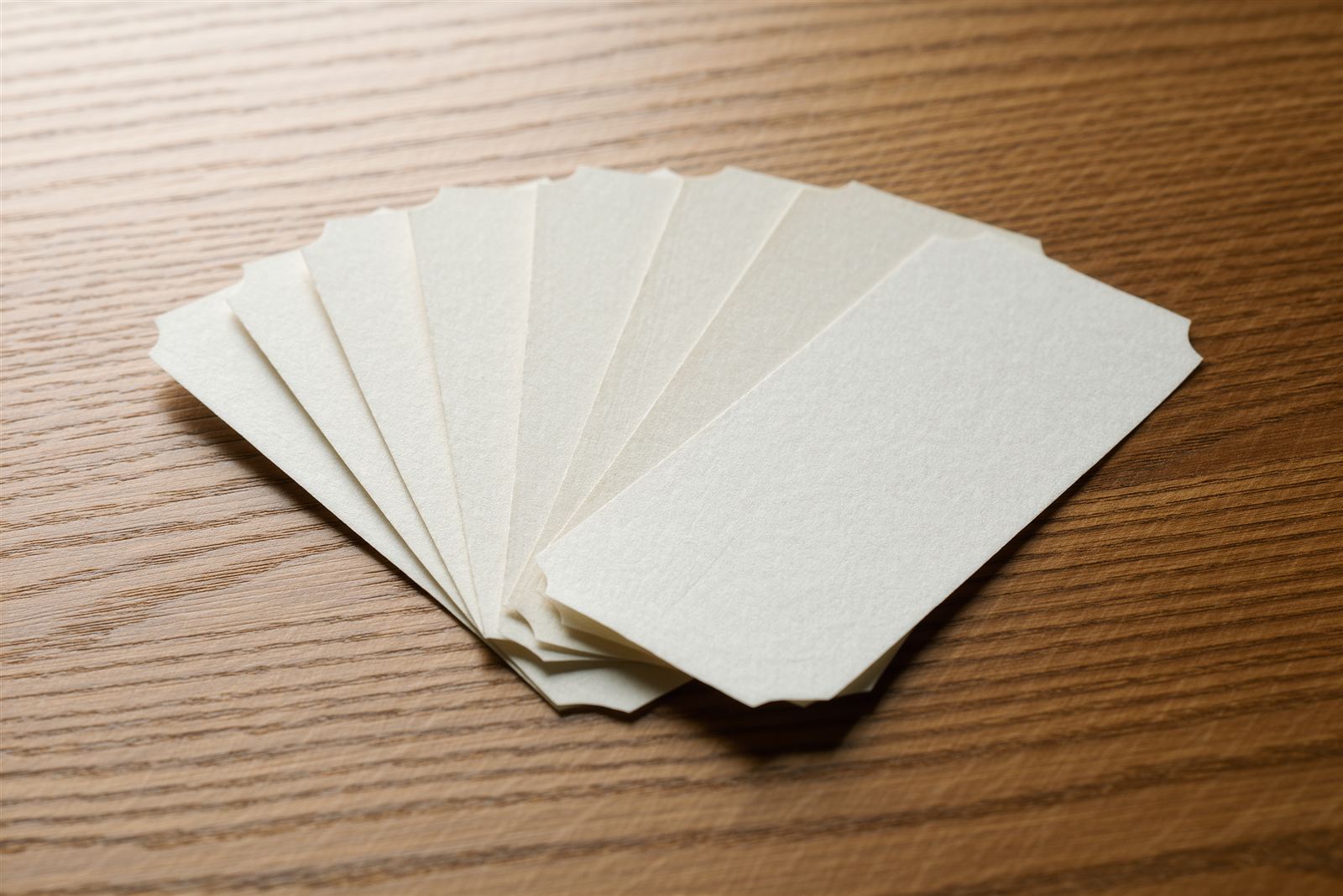 A fan of blank cream paper tickets on a wooden table